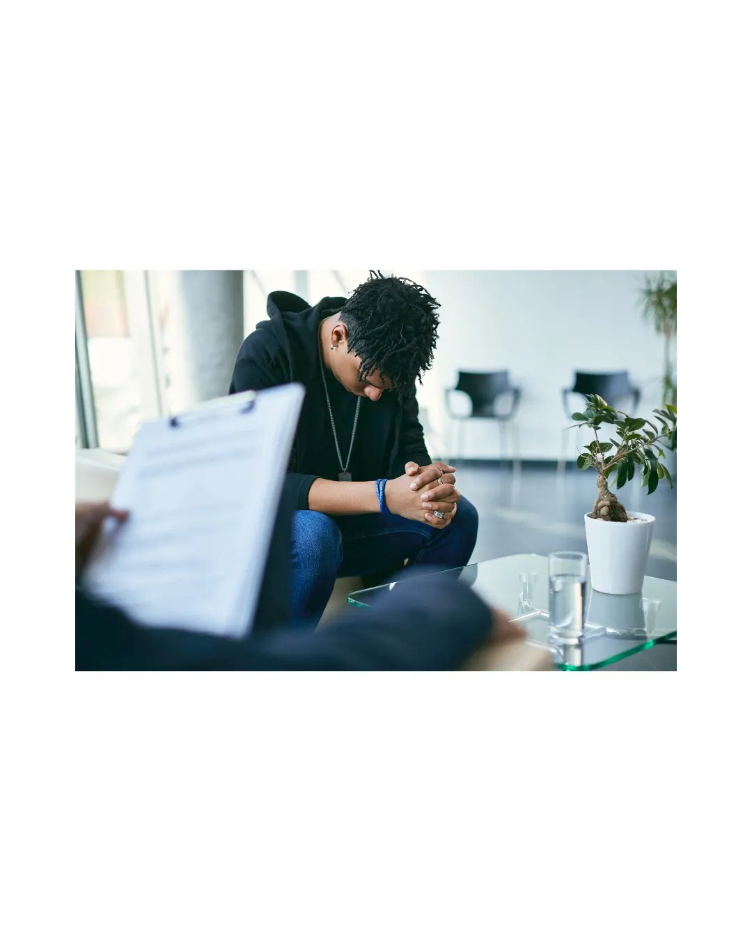 A young man sitting with his head bowed in a therapy session